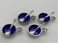 Top view of four salt cellars with matching spoons arranged