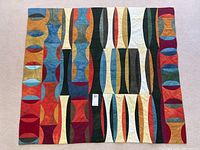 Full view of quilt showing abstract geometric design in multiple colors