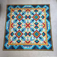Full view of quilt laid flat showing entire geometric diamond pattern