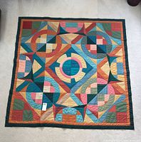 Full view of square quilt laid flat showing entire geometric design and border