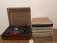 Overall view of turntable with dust cover and stack of vinyl records