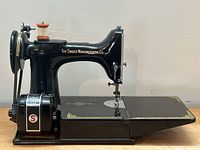 Side profile view of black Singer 221 Featherweight sewing machine on extended base