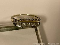 Top-angle view of ring showing five diamonds and filigree setting