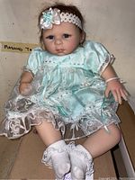Full body image of the doll seated, showing outfit, socks, and headband