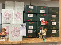 Stacked boxes of Boyd's Bears and Cherished Teddies with two example Boyd's Bear figures displayed. Figures depict a bear raising the Canadian flag with a dog.