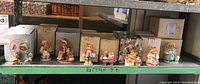 Shelf showing rows of Cherished Teddies figure boxes and some figurines in front, displaying the variety and quantity in the lot.