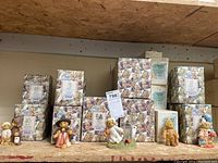 Shelf display of numerous boxes of Cherished Teddies figurines, with five figurines displayed in front on a wooden shelf.