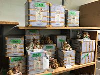 Shelf display of multiple boxed and unboxed Cherished Teddies figurines, showing original decorative packaging boxes and figurines placed nearby labeled with character names.