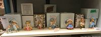 Photo of the full set of 7 different Cherished Teddies figurines displayed on shelf with original boxes behind