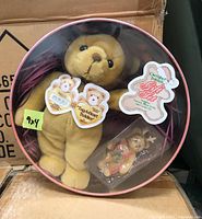 Photo showing one Cherished Teddies gift set with plush teddy bear and small holiday teddy figurine ornament inside round cookie tin with clear cover.