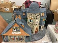 Front angle showing the architectural details and the shop name 'Maggie's Millinery'.