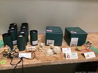 Overview of twelve figurines with original packaging in green boxes and cylinder containers.