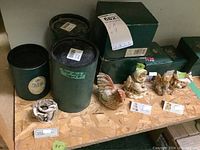 Green cylindrical boxes with Harmony Kingdom labels and seven figurines on display showing variety and packaging.