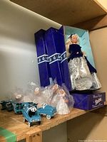 Four boxed Winter Velvet Barbie dolls visible on a wooden shelf; Barbie dolls wear blue velvet tops with silver patterned skirts; Original blue Mattel boxes show 'Winter Velvet Barbie' branding.