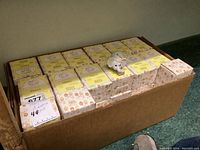 Box of approximately 44 boxed Precious Moments 'Pack Your Trunk for the Holidays' ornaments stacked inside a larger cardboard box.