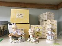 Photo showing 3 Precious Moments figurines with their original boxes stacked behind them on a shelf.