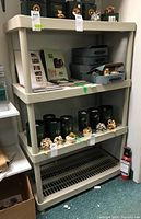 Photo of the resin shelving unit with four levels, containing various items (not included) for scale and context.