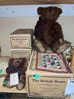 Four brown mohair bears shown with their cream colored boxes and one quilted patchwork cloth under the large bear.