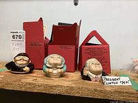 Three ceramic face pots with lids displayed with original red boxes. Faces include London Bobbi, President Clinton, and old lady.