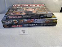 Stacked photo showing the three Monopoly games: Cheaters Edition on top, Yukon-themed game in middle, Night Sky Edition at bottom.