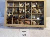 Top view of the wooden display case showing rows of various rocks and mineral specimens separated into individual compartments.
