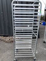 Front view of commercial aluminum tray holder rack with multiple tray slots and caster wheels.