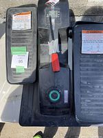 Top view showing two black pedals with warning labels on each, central panel with red screwdriver, adjustment dial, and digital display.