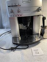 Front view of machine showing housing, control panel, drip tray, milk pitcher, power cord