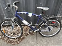 Side view of men's blue Impulse bicycle showing frame, handlebars, seat, wheels, and front fork.