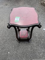 Front view of wooden table with red leather top, showing carved legs and nailhead trim