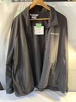 Front view of the black Columbia jacket showing full front zipper, two zippered side pockets, and Columbia logo on left chest.