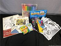 Collection of multiple art supplies including drawing pads, crayons, markers, activity sheets, and instruction book