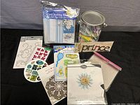 Photo showing an overview of 10 crafting items including card making kit, stickers, embellishments, wooden cutout, felt balls, and feathers.