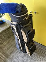 Black and beige System Golf golf bag standing upright with visible logo, zippered pockets, and strap