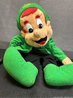 Front view of Lucky the Leprechaun plush backpack showing detailed facial features and bright green costume.