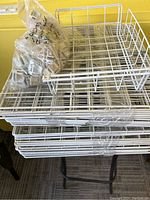 Stack of white metal wire rack shelves with sides forming cubed shelving.