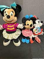 Image showing all three Minnie Mouse plushies lined up, displaying size and outfit differences.