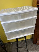 Front view of white plastic storage unit with four drawers stacked, showing translucent drawer fronts and ridged top surface.