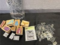 Wooden rubber stamps with colorful designs including shoe, dress, necklace, and a castle, plus black and white religious themed stamps and packaging.