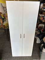 Front view of the closed white cabinet showing two doors and handles.