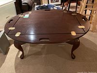 Front angled view showing the dark wood, gold hinges on top, and carved legs.