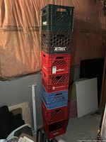 Stacked view of all seven crates showing mixed colors and brands in a basement setting.