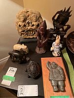 Various figurines arranged together showing dogs, turtle, elephant, carved mountain scene, and faux soapstone mounted figure.