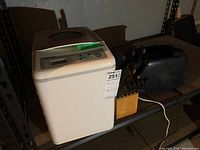 White Black and Decker bread maker, black toaster and wooden knife block with knives on a shelf