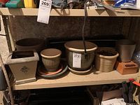 Six ceramic plant pots of various sizes arranged on a shelf, showing different shapes and colors.