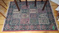 Top view of rectangular oriental area rug with patchwork floral and geometric pattern, in red, green, beige, and blue shades.