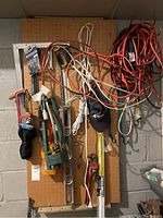 Full view of pegboard with various tools hung including red pipe wrench, yellow level, T-square, extension cords, and saws