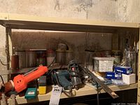 Shelf with Black and Decker heat tool, Bosch glue gun, staple tool, saw blades, and plastic containers with hardware items in the background.