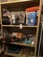 Shelf view showing variety of tools, household items and tool cases, including Black and Decker sander and some glass jars.