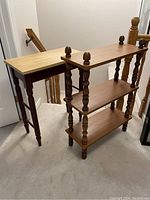 Photo of two vintage wooden knickknack shelves, one light-colored with tapered legs, and one darker with three tiers and turned spindle legs topped with finials.